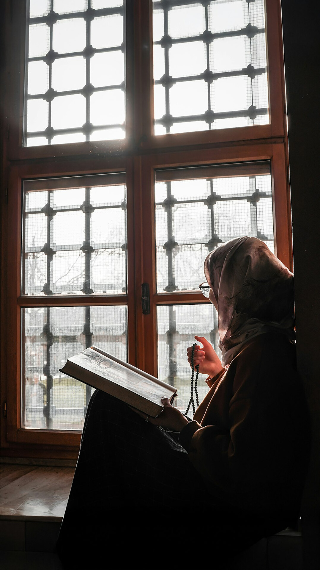 person reading old book by window